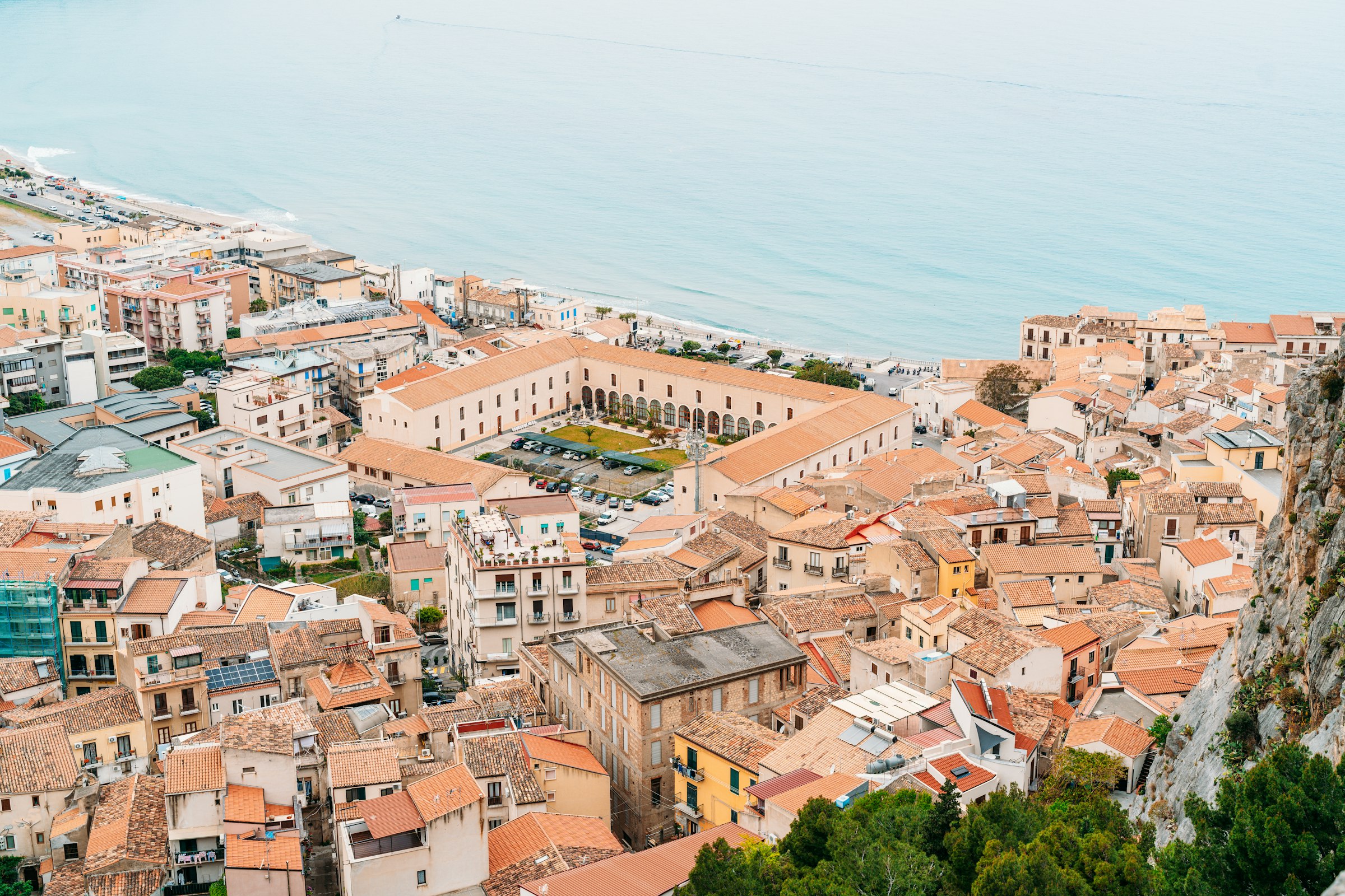 Dense rooftops of a coastal town seen from above, next to the sea
